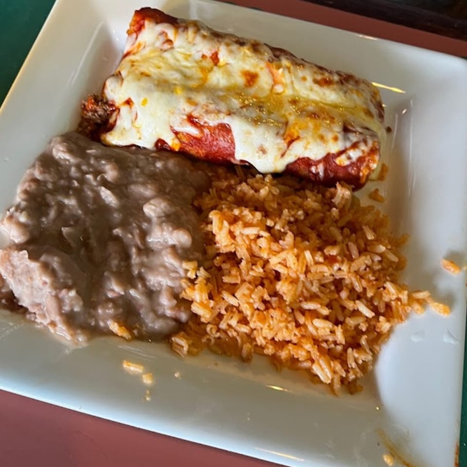A Dos Pesos Mexican Restaurant plate with a cheesy enchilada, refried beans, and Spanish rice.