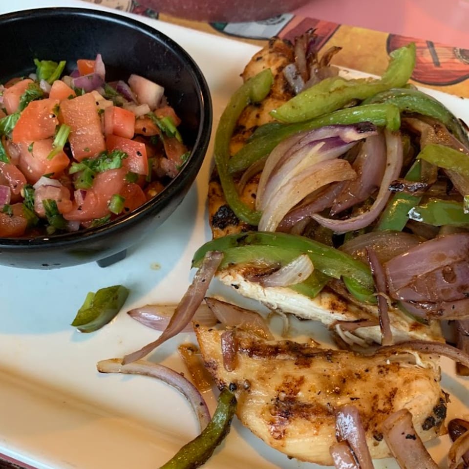 Grilled chicken fajitas with sautéed onions and bell peppers, served with a side of fresh pico de gallo.